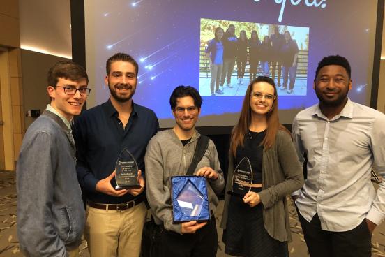 Five students posing, holding three crystal awards