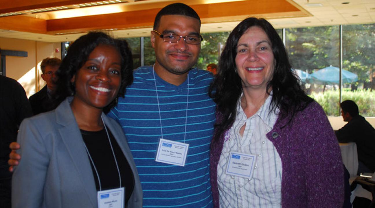 Three people standing shoulder-to-shoulder, smiling and posing