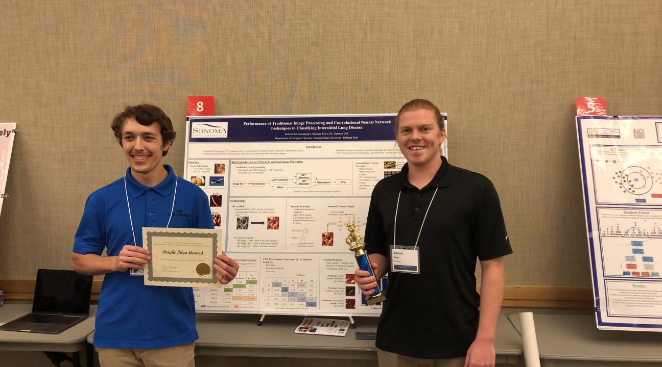 Two students receiving an award, posing in front of a research poster