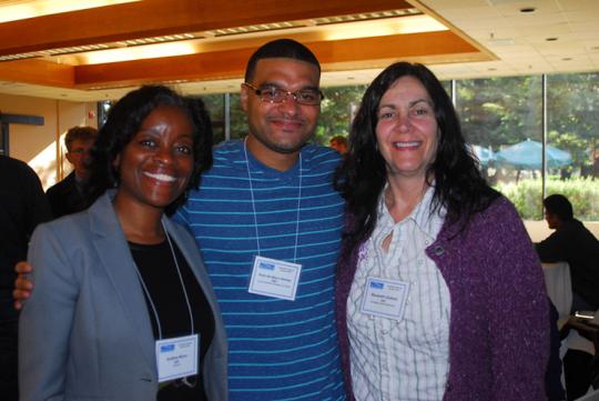Three people standing shoulder-to-shoulder, smiling and posing